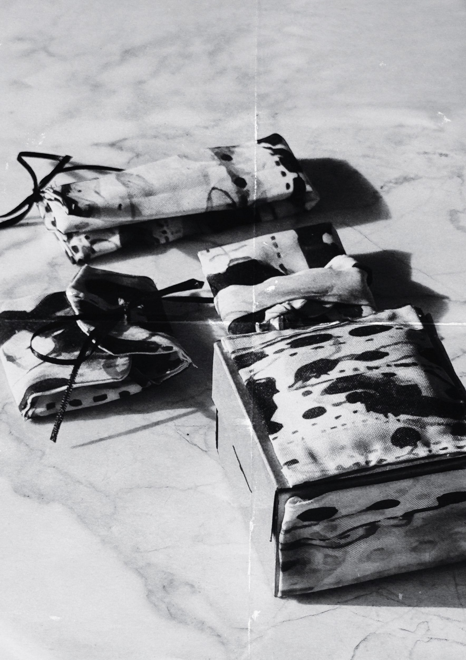 Las cuatro piezas del Archivo .925 envueltas en tela estampada como empaque final, fotografiadas sobre mármol.